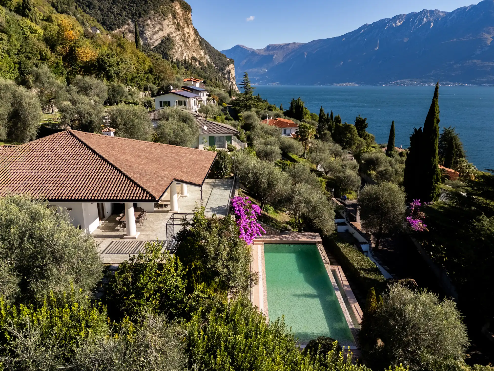 Aerial view of Villa Giulia with its pool and olive grove above Lake Garda, mountains on the horizon