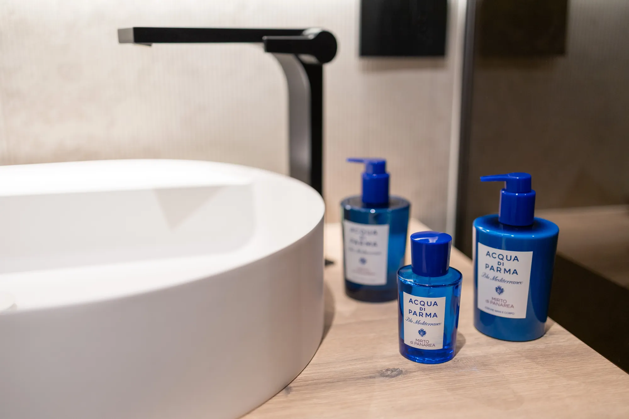 Acqua di Parma toiletries beside a white vessel basin