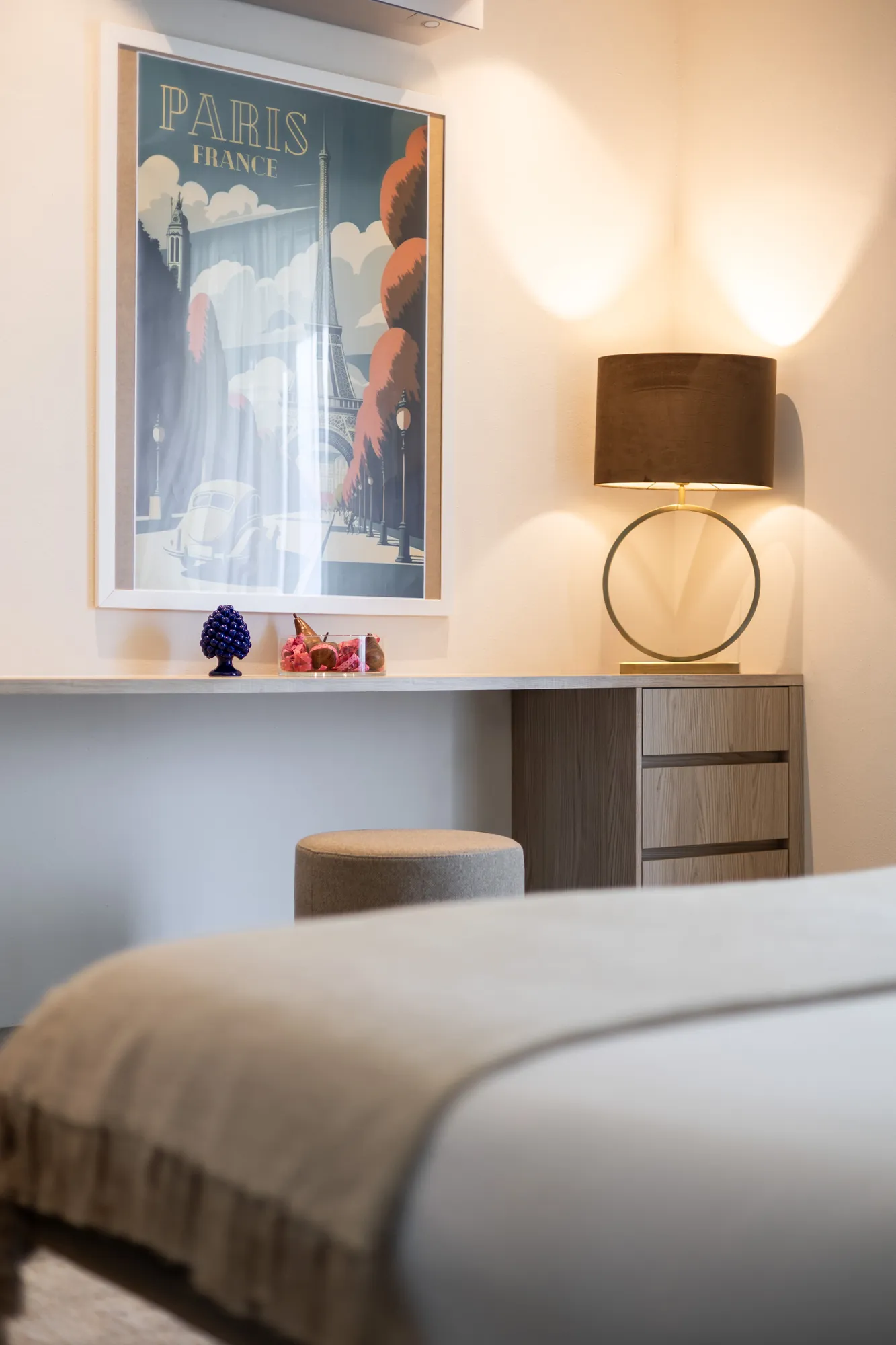 Bedroom corner with Paris travel poster, table lamp and pouf