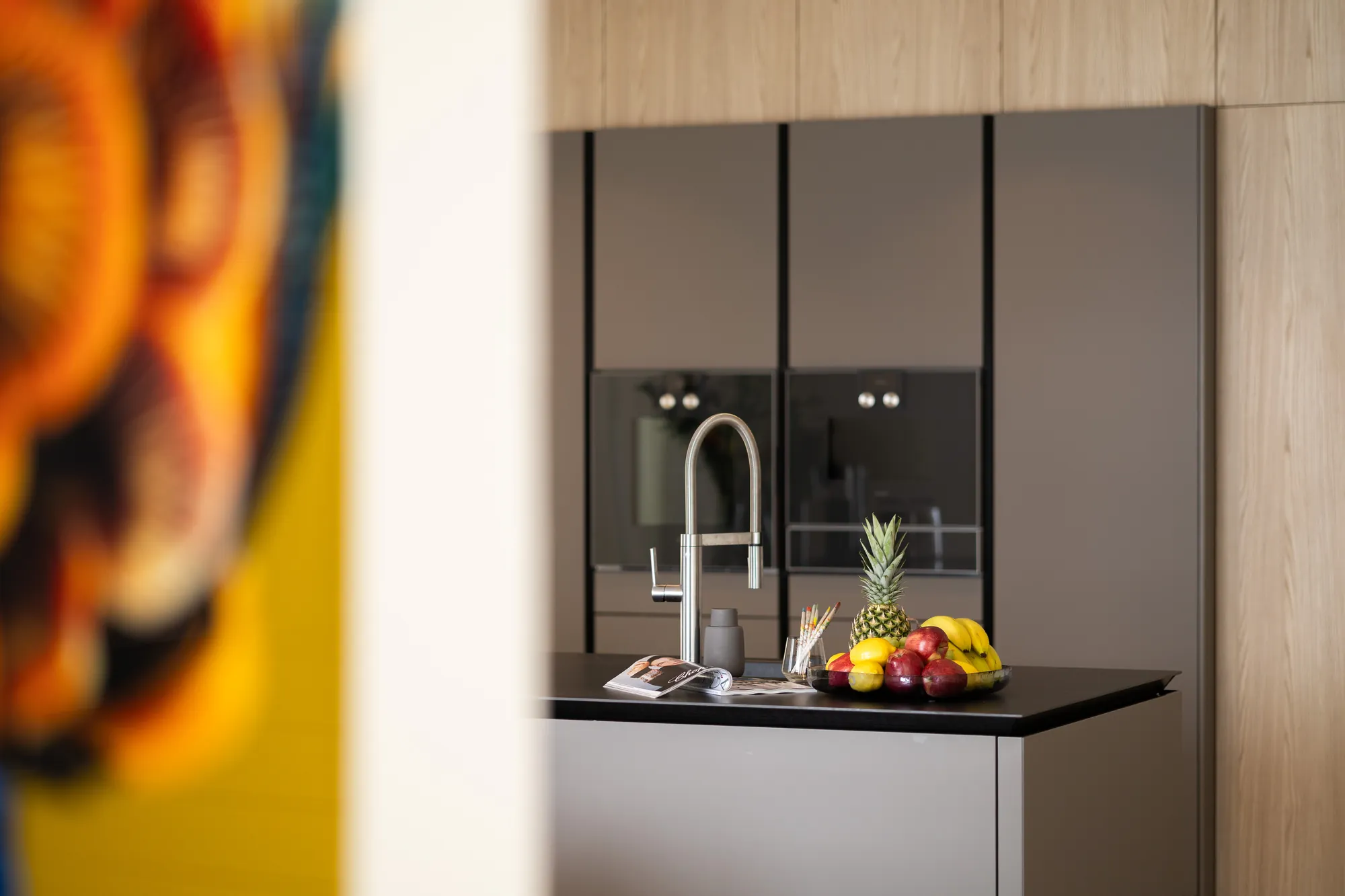 Kitchen detail with chrome tap and fresh fruit on the black worktop