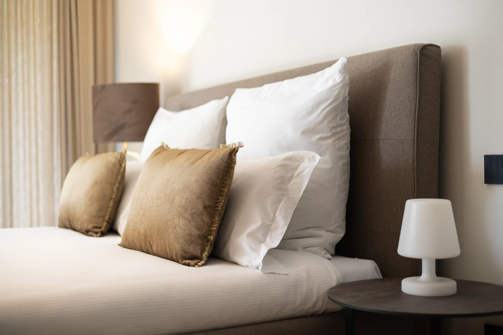 Bed with crisp white linen and golden velvet cushions