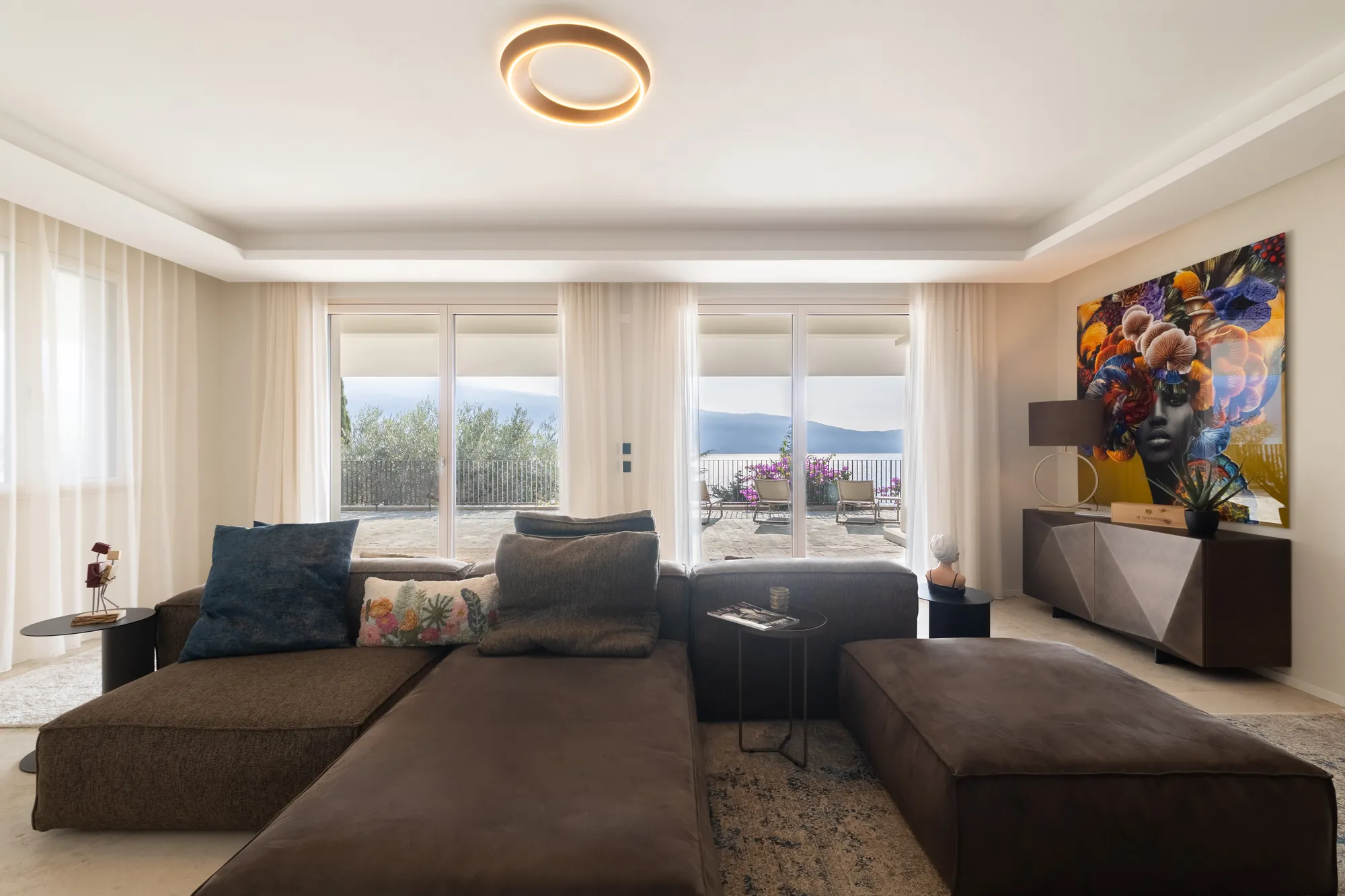 Living room with deep sofa and floor-to-ceiling windows opening onto the terrace and Lake Garda