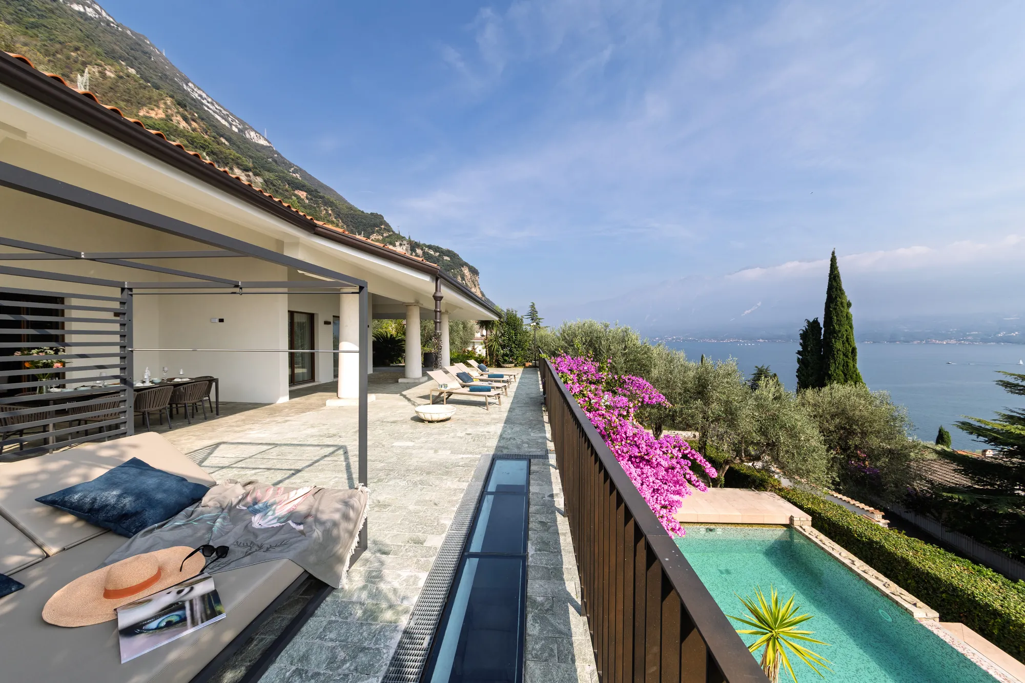 Long sun terrace above the pool with bougainvillea and views across Lake Garda