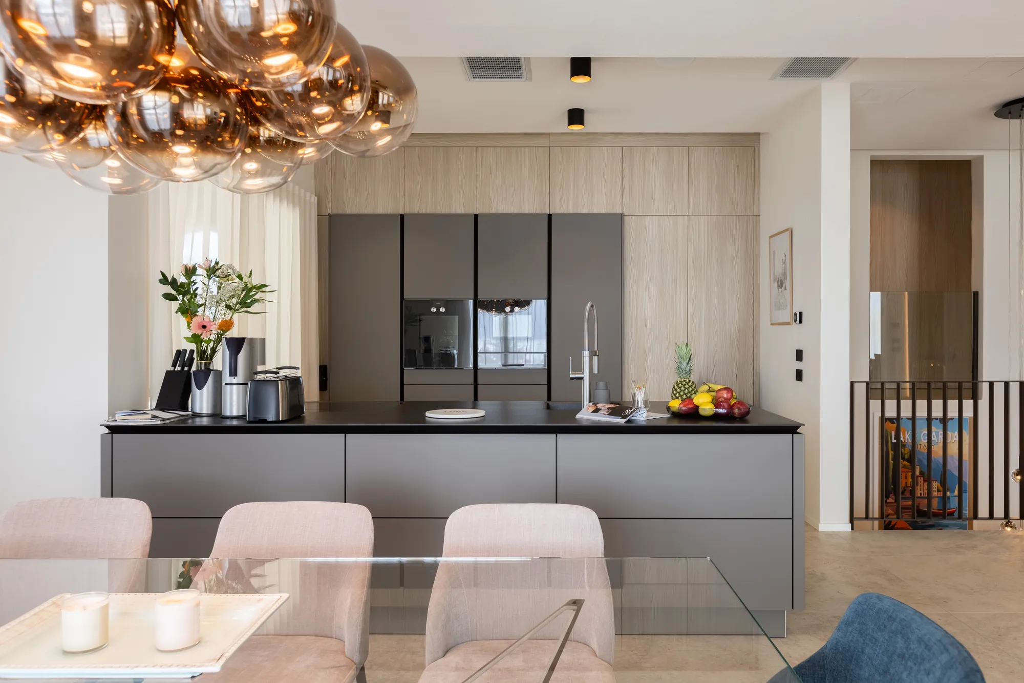 Designer kitchen with dark island, built-in ovens and copper pendant light