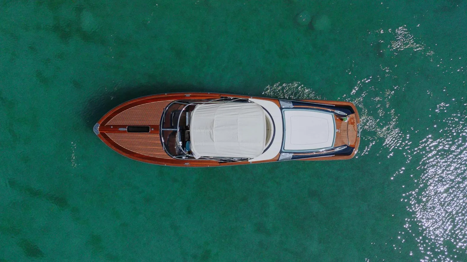A classic Riva motorboat seen from above on the clear green water of the lake